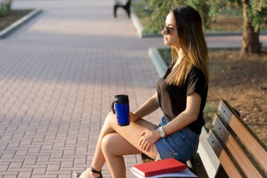 Genç bir kız parkta bir bankta oturur ve notlar yapar. Serbest stilde giyinmiş. Müşterilerle telefonda konuşan iş kadını.