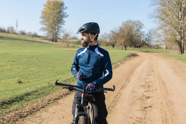 Cyclist in pants and fleece jacket on a modern carbon hardtail bike with an air suspension fork rides off-road.