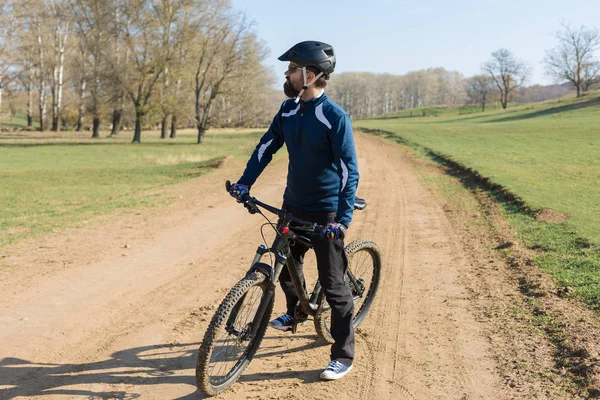 Cyclist in pants and fleece jacket on a modern carbon hardtail bike with an air suspension fork rides off-road.