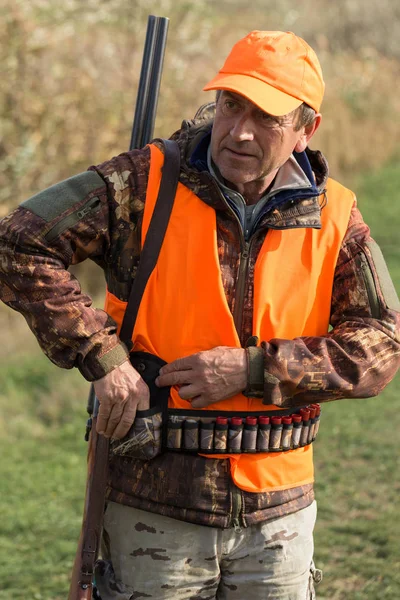 Elinde Silahı Olan Bir Avcı Yansıtıcı Turuncu Yelekli Bir Köpeği — Stok fotoğraf