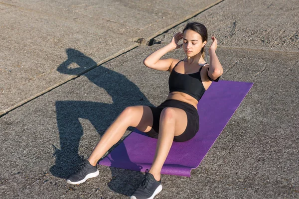 A thin athletic girl takes a break between classes on the background of the building in the early morning, enjoys silence and freedom.