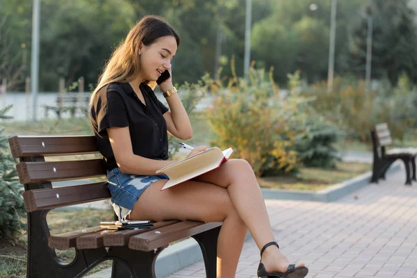 Uma Jovem Senta Banco Parque Faz Anotações Vestido Estilo Livre — Fotografia de Stock