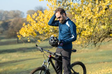 Pantolon ve yün ceketli bir bisikletçi. Havalandırma çatallı, modern bir karbon motorlu. Tepedeki adam bisiklete biniyor..