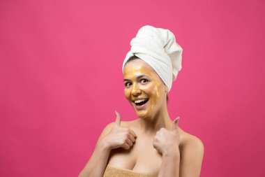 Yüzünde altın besleyici maske olan beyaz havluyla kadın portresi. Cilt temizleme eko organik kozmetik rahatlama konsepti.