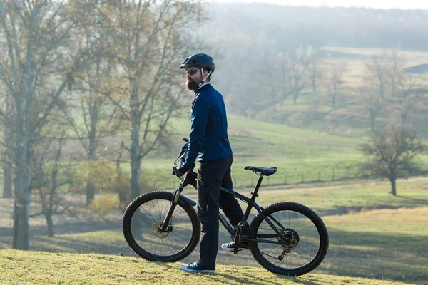 Cyclist in pants and fleece jacket on a modern carbon hardtail bike with an air suspension fork. The guy on the top of the hill rides a bike.