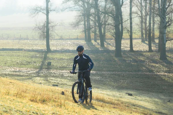 Cyclist in pants and fleece jacket on a modern carbon hardtail bike with an air suspension fork. The guy on the top of the hill rides a bike.