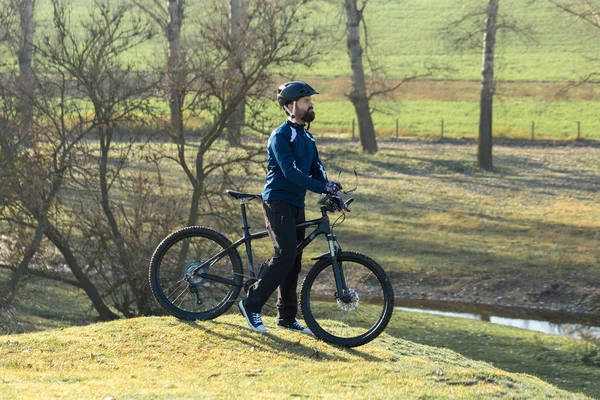 Cyclist in pants and fleece jacket on a modern carbon hardtail bike with an air suspension fork. The guy on the top of the hill rides a bike.