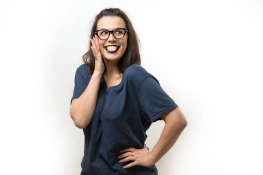 Gözlüklü romantik kız utangaç bir gülümsemeyle poz veriyor. Beyaz arkaplanda stüdyonun yakın plan portresi.