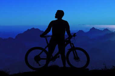 Şort ve mayo modern bir karbon hardtail bisiklet üzerinde bir hava süspansiyon çatal sürmek off-road turuncu-kırmızı tepelerde yaz aylarında gün batımı akşamı