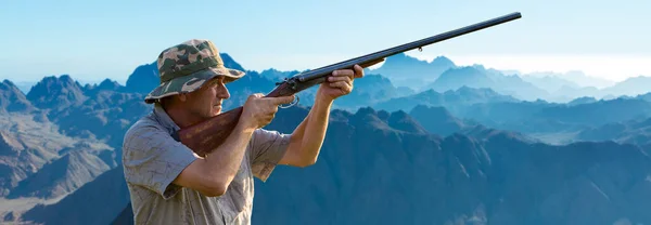 一个身穿迷彩服的猎人手里拿着枪站在山顶上寻找目标 美丽的山景 狩猎的开始 — 图库照片