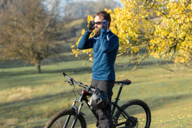 Pantolon ve yün ceketli bir bisikletçi. Havalandırma çatallı, modern bir karbon motorlu. Tepedeki adam bisiklete biniyor..