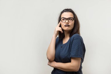 Gözlüklü heyecanlı genç bayanın görüntüsü. Kameranın bir fikri var. Beyaz bir arkaplanda durur.