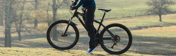 Cyclist in pants and fleece jacket on a modern carbon hardtail bike with an air suspension fork. The guy on the top of the hill rides a bike.