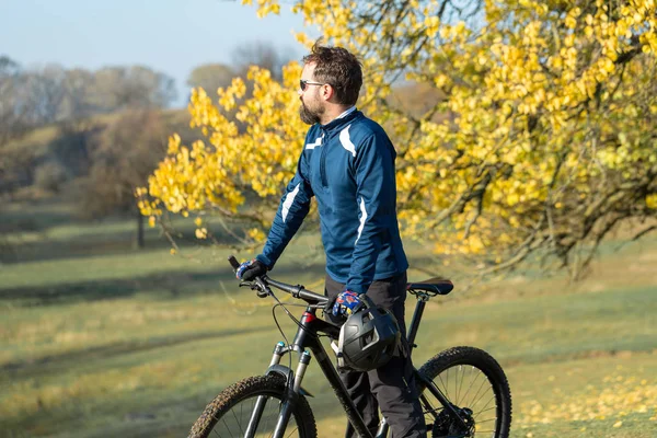 Cyclist in pants and fleece jacket on a modern carbon hardtail bike with an air suspension fork. The guy on the top of the hill rides a bike.