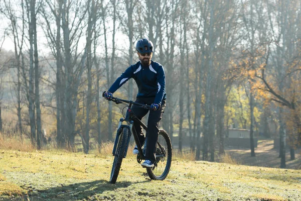 Cyclist in pants and fleece jacket on a modern carbon hardtail bike with an air suspension fork. The guy on the top of the hill rides a bike.