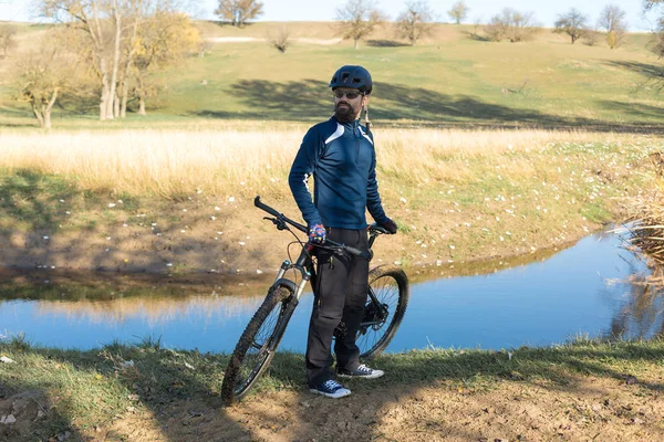 Cyclist in pants and fleece jacket on a modern carbon hardtail bike with an air suspension fork rides off-road.