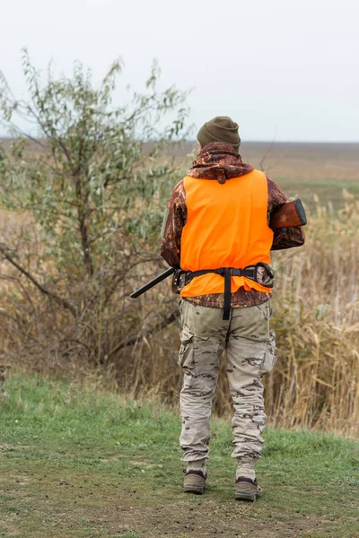 나무가 우거진 날씨에 오렌지 조끼를 남자가 나무가 우거진 지역에서 사냥을 — 스톡 사진