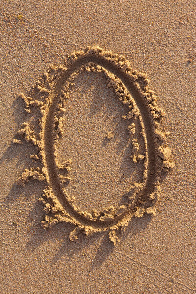 Alphabet letters handwritten in sand on beach