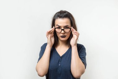 Gözlüklü heyecanlı genç bayanın görüntüsü. Kameranın bir fikri var. Beyaz bir arkaplanda durur.
