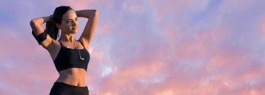 İnce atletik bir kız gün batımında güzel gökyüzünün arka planında dersler arasında sessizlik ve özgürlüğün tadını çıkarıyor..