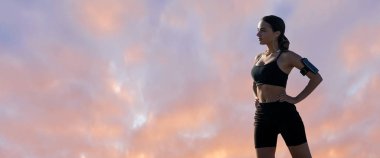 İnce atletik bir kız gün batımında güzel gökyüzünün arka planında dersler arasında sessizlik ve özgürlüğün tadını çıkarıyor..