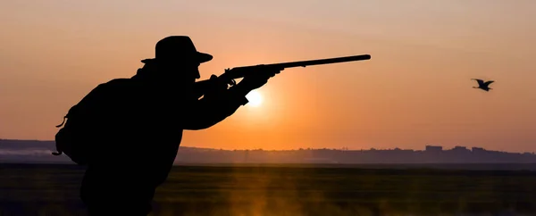 在晨曦的背景下 一个猎人的轮廓 拿着枪站在待命状态 — 图库照片