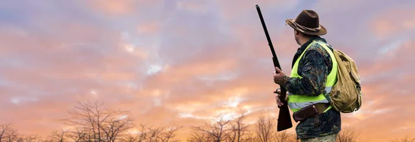 Kızıl Şafağın Arka Planında Bir Avcının Silueti Elinde Silahla Hazır — Stok fotoğraf