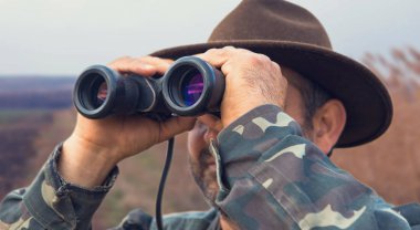 Dürbünlü bir avcı güzel bir akşamın arka planında avını arar..