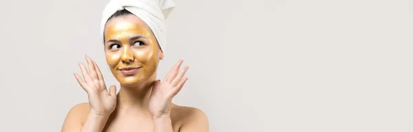 顔に金栄養マスクを頭の上に白いタオルの女性の美しさの肖像画 スキンケアクレンジングエコ有機化粧品スパリラックスコンセプト — ストック写真