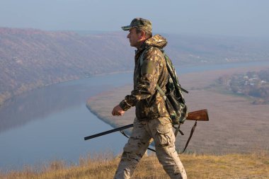 Avlanırken av sırasında av hayvanı ya da av hayvanı arayan kamuflajlı bir avcı. Sonbahar av sezonu.