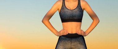 Genç eğitimli ince bir kız dağlarda güzel bir gün batımının karşısında duruyor..