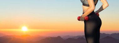 Genç eğitimli ince bir kız dağlarda güzel bir gün batımının karşısında duruyor..