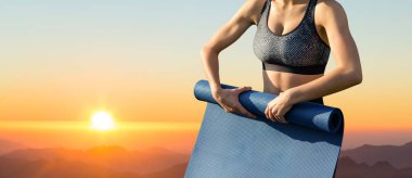 Genç eğitimli ince bir kız dağlarda güzel bir gün batımının karşısında duruyor..