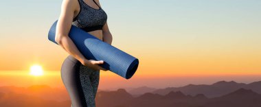 Genç eğitimli ince bir kız dağlarda güzel bir gün batımının karşısında duruyor..