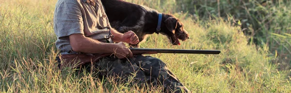 手に銃を持った男と曇りの日に森の中でキジ狩りをする緑のベストゲームを求めて犬とハンター — ストック写真