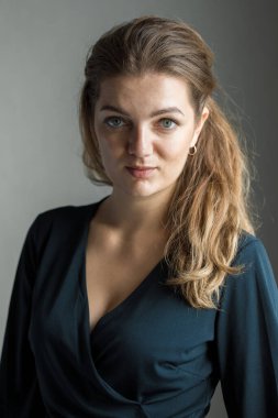 Arka planda, gölgeli gri bir duvarın üzerinde, penceresinden yansıyan doğal ışık olan güzel bir kızın portresi..