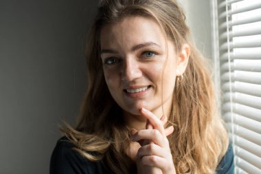 Arka planda, gölgeli gri bir duvarın üzerinde, penceresinden yansıyan doğal ışık olan güzel bir kızın portresi..