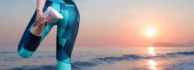 Sıska bir atletik kız, gün batımının arka planında, sabah erkenden deniz kenarında derslere ara verip sessizliğin ve özgürlüğün tadını çıkarıyor..