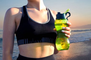 Sıska bir atletik kız, gün batımının arka planında, sabah erkenden deniz kenarında derslere ara verip sessizliğin ve özgürlüğün tadını çıkarıyor..