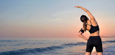 Sıska bir atletik kız, gün batımının arka planında, sabah erkenden deniz kenarında derslere ara verip sessizliğin ve özgürlüğün tadını çıkarıyor..