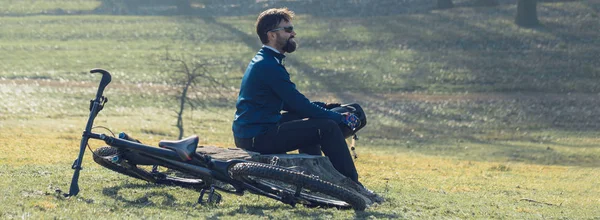 エアサスフォーク付きのモダンなカーボンハードテールバイクのパンツとフリースジャケットでサイクリスト 丘の上の男は自転車に乗っている — ストック写真