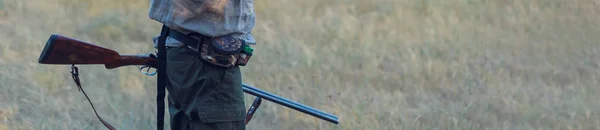 一个人手里拿着枪 穿着绿色背心 在多云的天气里在森林里猎杀野鸡 带着狗寻找猎物的猎人 — 图库照片