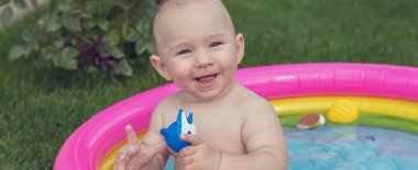 Küçük bir çocuk havuzda banyo yapıyor, yazın şişme çocukların şişme havuzunda.