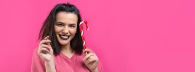 Güzel, güzel, neşeli, düz kahverengi saçlı bir kadının portresi. Kırmızı şeker kamışı Noel 'ini ısırmaya çalışıyor..