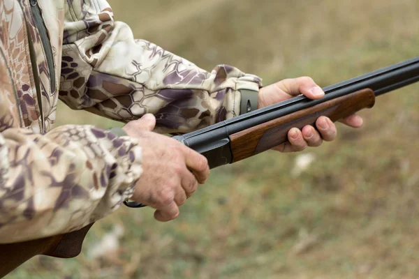 Charges a hunting smooth-bore rifle, hunting a pheasant with dogs. A hunter in camouflage is standing with a weapon.