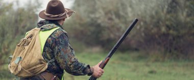 Alman bir drathaar ve spanyel ile avcılar, yansıtıcı yelek giymiş köpeklerle güvercin avlıyorlar.