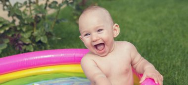 Küçük bir çocuk havuzda banyo yapıyor, yazın şişme çocukların şişme havuzunda.