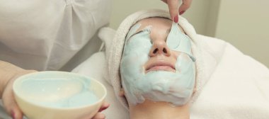 Yüz bakımı. Güzellik uzmanı güzellik salonunda fırça kullanarak yüzüne güzellik maskesi takıyor.