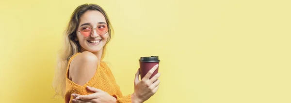 オレンジのセーターに身を包んだグラマーな女性 黄色の背景にコーヒーを飲みながら — ストック写真