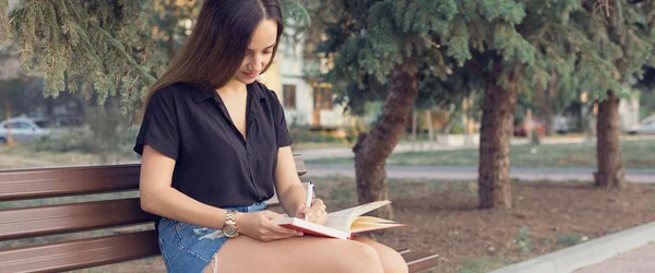 Uma Jovem Senta Banco Parque Faz Anotações Vestido Estilo Livre — Fotografia de Stock